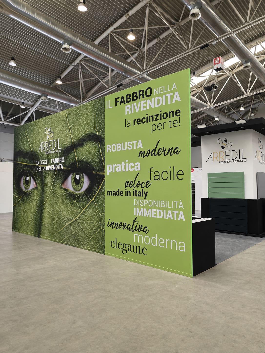 Parete grafica verde con il messaggio “Il fabbro nella rivendita” vista dalla corsia