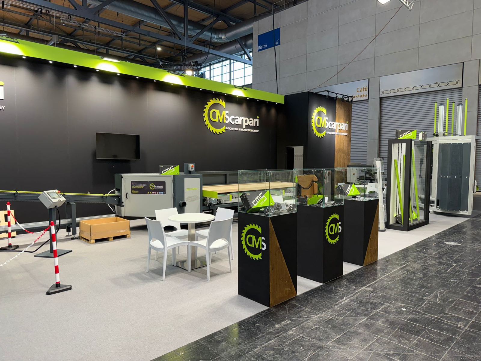 Glass cases on branded plinths with components, and a meeting area with a white table and chairs