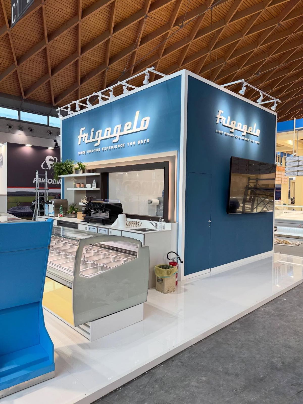 Volume blu con il logo Frigogelo, monitor e vetrina per il gelato visto dalla corsia