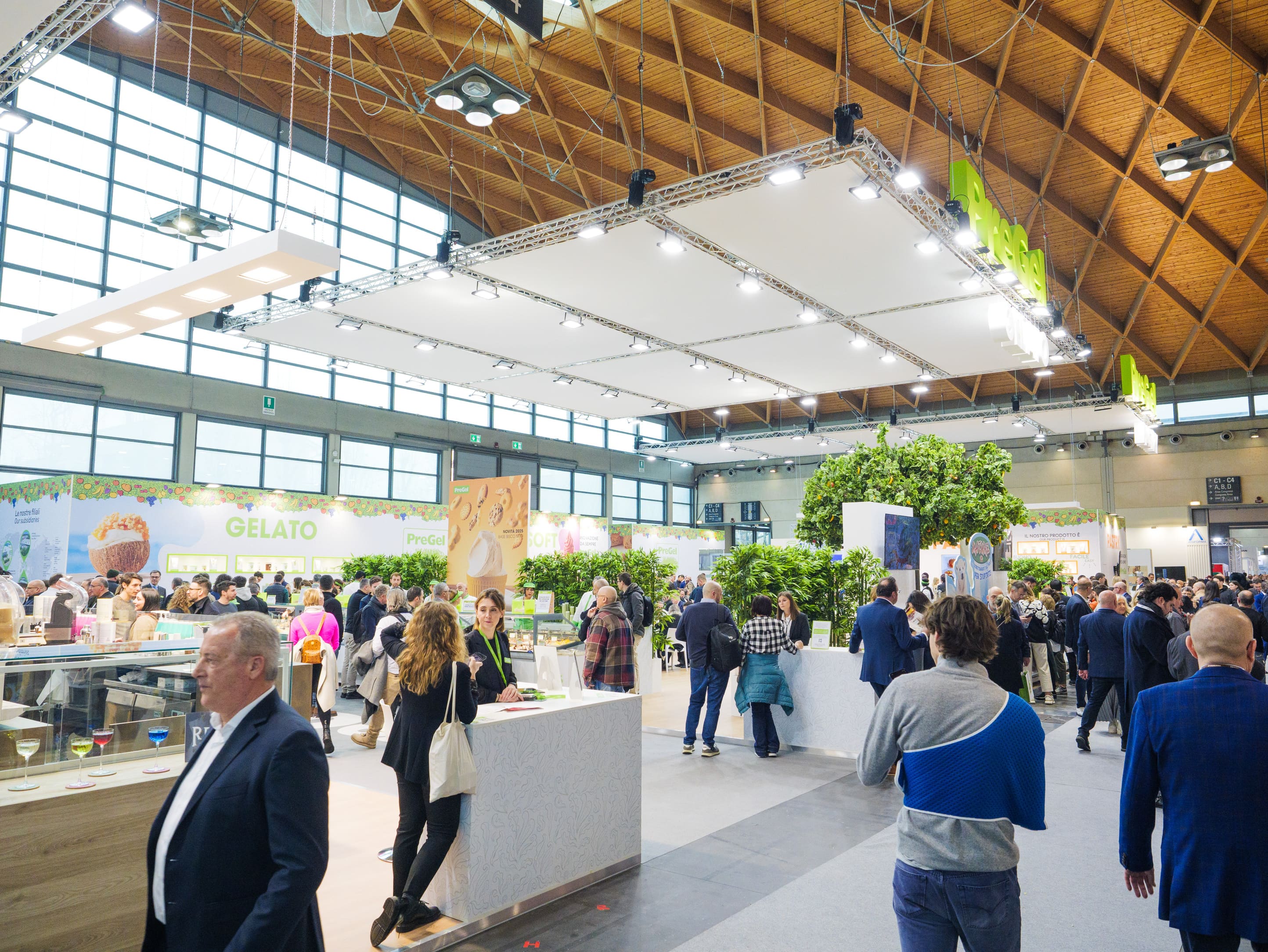 Visitatori nella piazza centrale dello stand PreGel, sotto la struttura sospesa con il logo