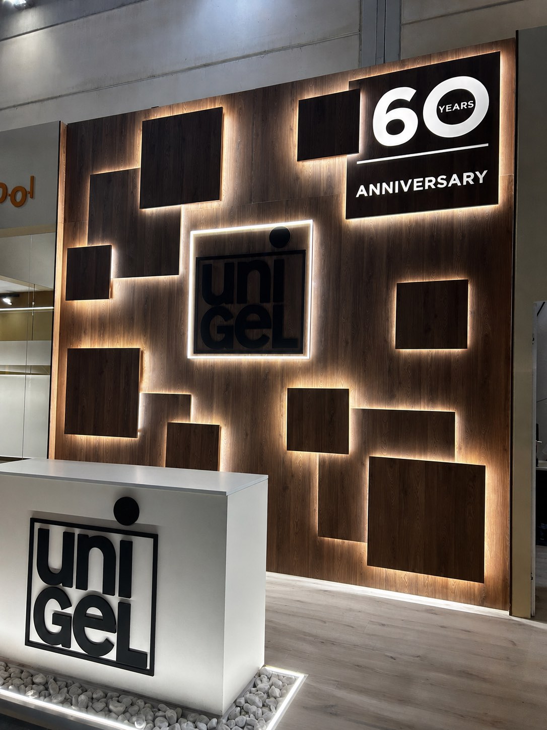 Parete decorativa in legno retroilluminata con il logo Unigel e la targa “60 years anniversary”